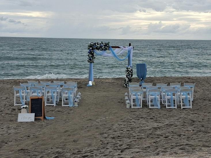 Beach wedding ceremony setup with a wedding arch and four rows of white chairs along the waters edge on Siesta key Beach in Sarasota Florida
