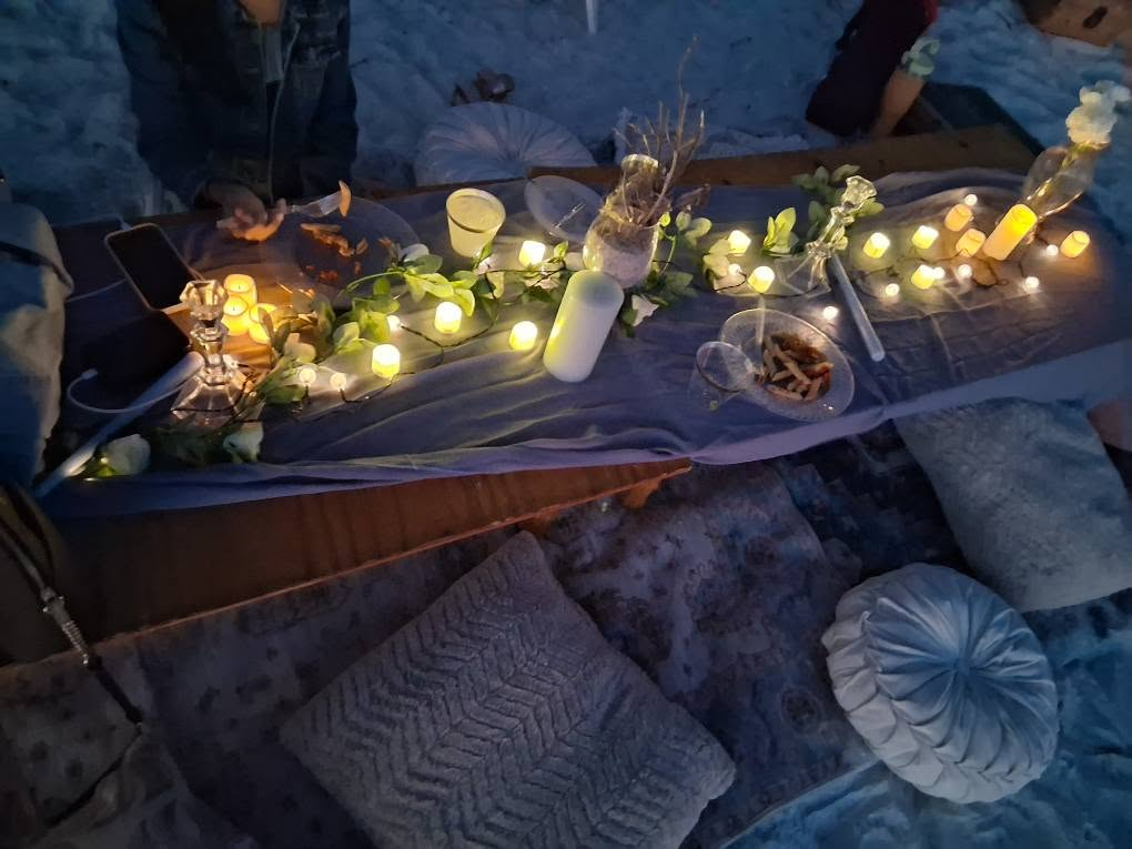 Romantic beach picnic setting with decorative lighting and thoughtfully arranged event details.