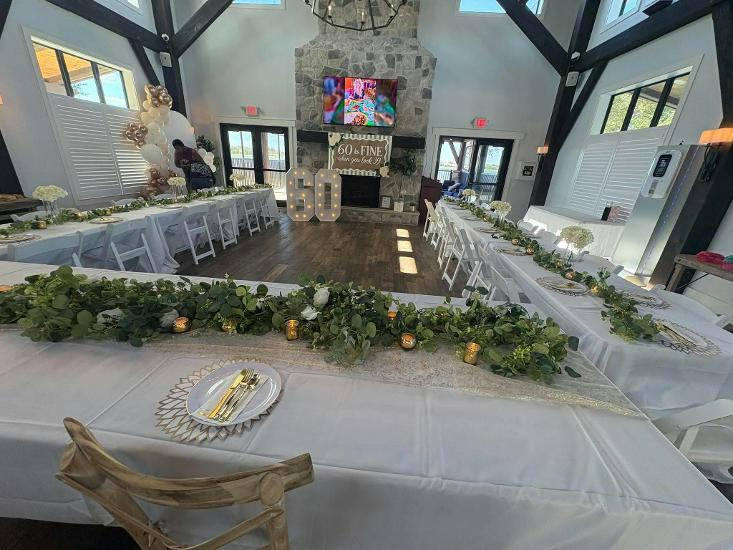 Indoor event venue decorated with tables, floral arrangements, and a stone firepplace for a special birthday celebration 