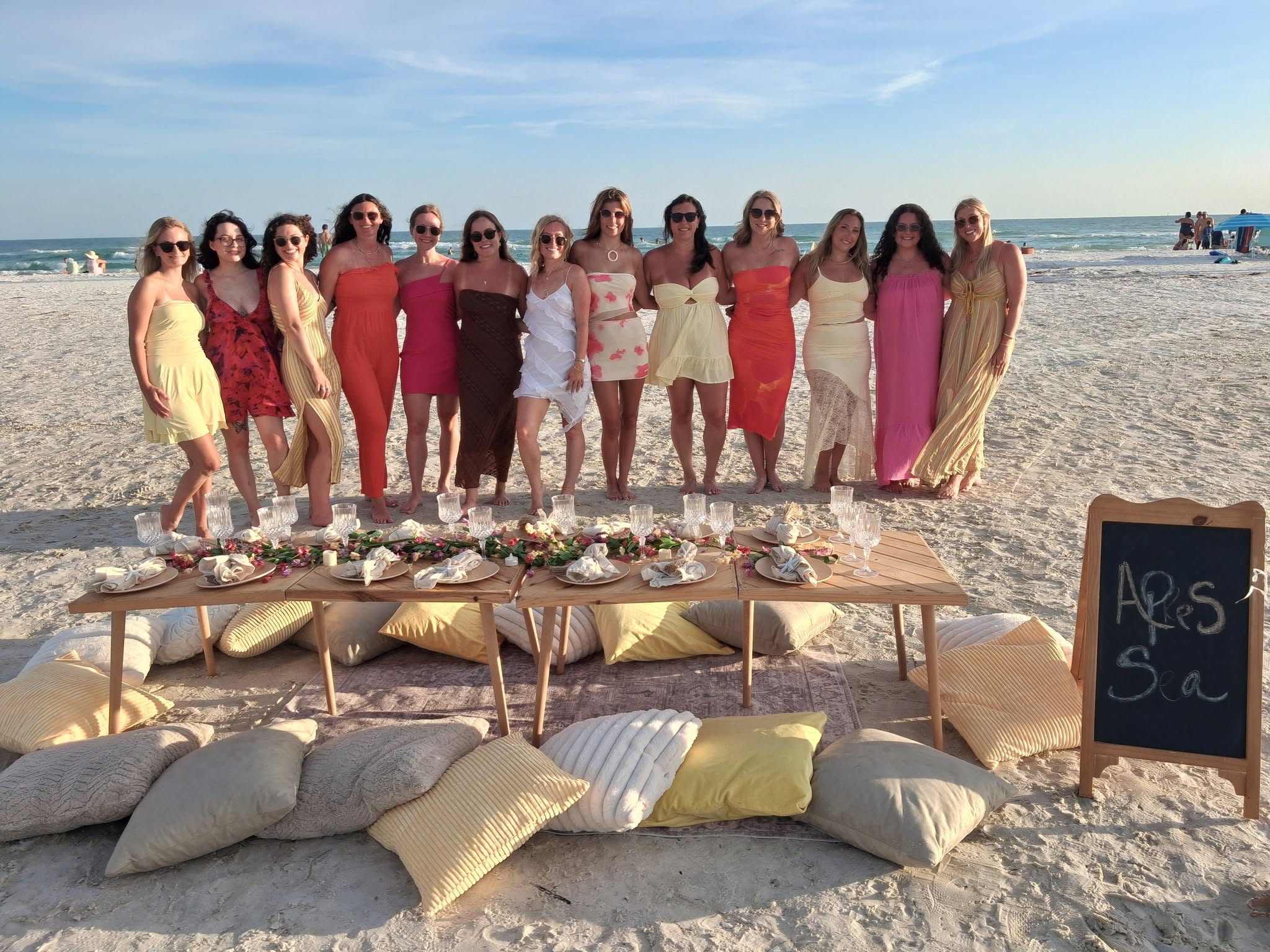 Wedding celebration with a group of women gathered behind an elegantly styled beach picnic table in Sarasota Florida